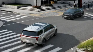 Kia Carnival màu bạc nhìn từ góc 3/4 phía sau.