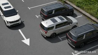Kia Carnival màu bạc góc 3/4 trước, nổi bật giữa bãi đỗ xe.