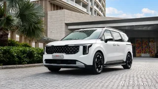 Kia Carnival màu trắng góc 3/4 trước, nổi bật giữa không gian hiện đại.
